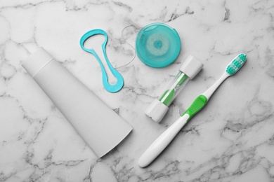 Flat lay composition with tongue cleaner and teeth care products on marble background