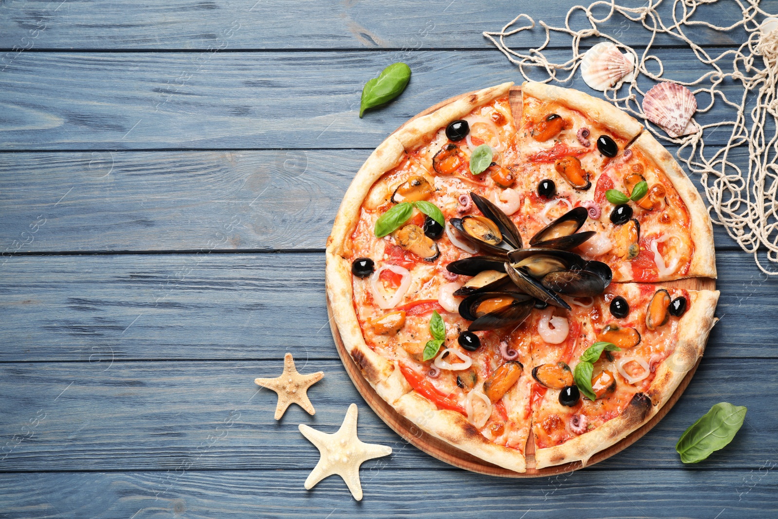 Photo of Tasty pizza with seafood and fresh basil on blue wooden table, flat lay. Space for text