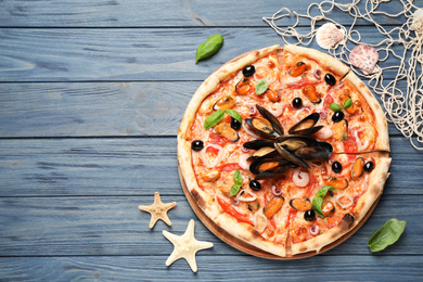 Photo of Tasty pizza with seafood and fresh basil on blue wooden table, flat lay. Space for text