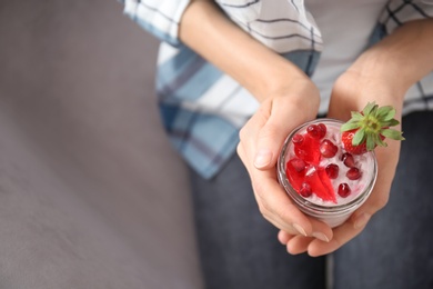 Young woman eating tasty yogurt with fruits, closeup