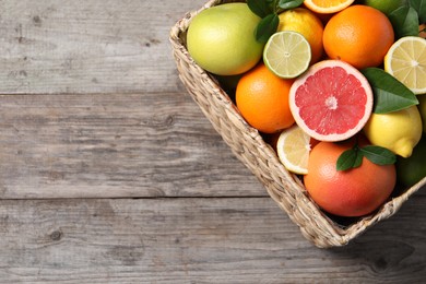 Photo of Different cut and whole citrus fruits on wooden table, top view. Space for text