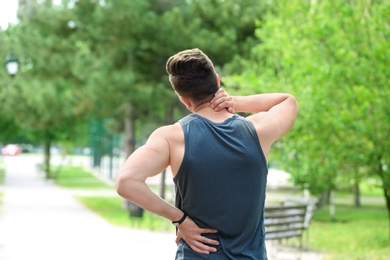 Photo of Man in sportswear suffering from back pain outdoors