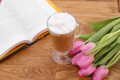 Photo of Glass of delicious cocoa, pink tulips and book on wooden table