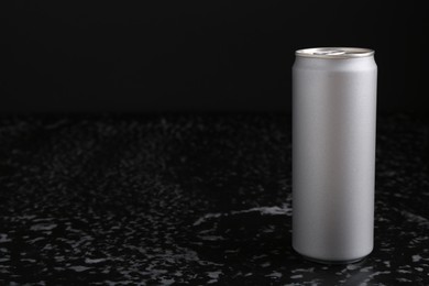 Photo of Energy drink in can on black textured table, space for text