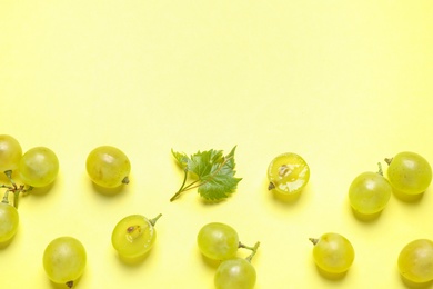 Flat lay composition with fresh ripe juicy grapes on yellow background, space for text