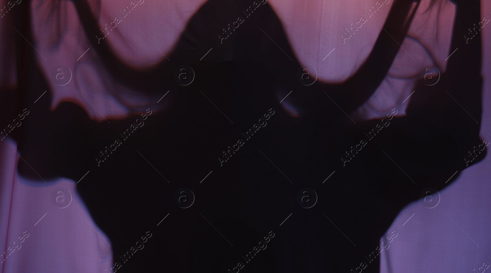 Photo of Silhouette of creepy ghost behind purple cloth