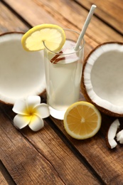 Photo of Composition with glass of coconut water and lemon on wooden table