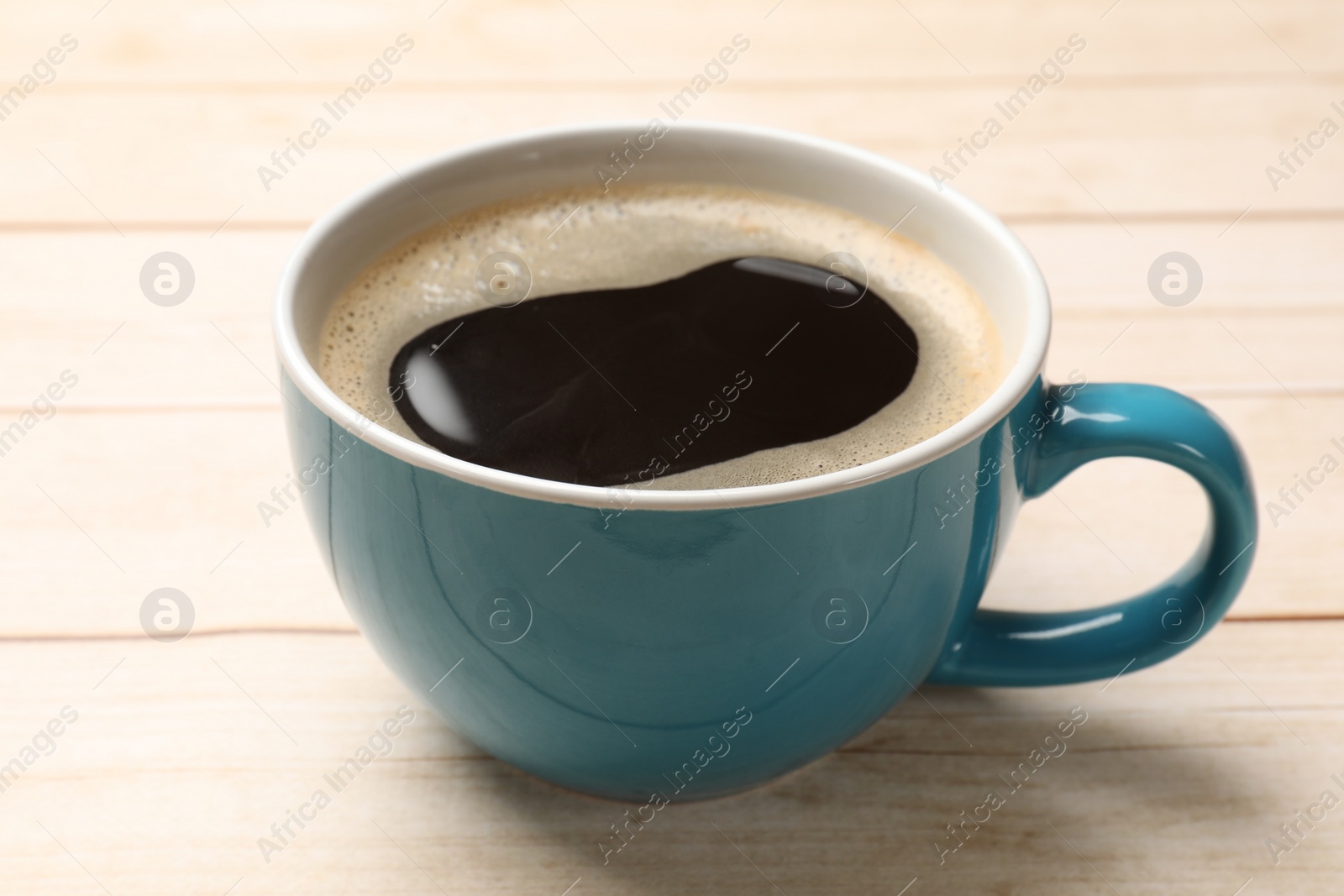 Photo of Cup of aromatic coffee on light wooden table, closeup