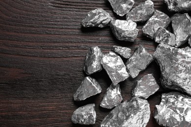Photo of Pile of silver nuggets on wooden table, flat lay. Space for text