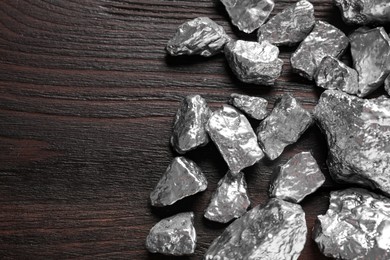 Pile of silver nuggets on wooden table, flat lay. Space for text