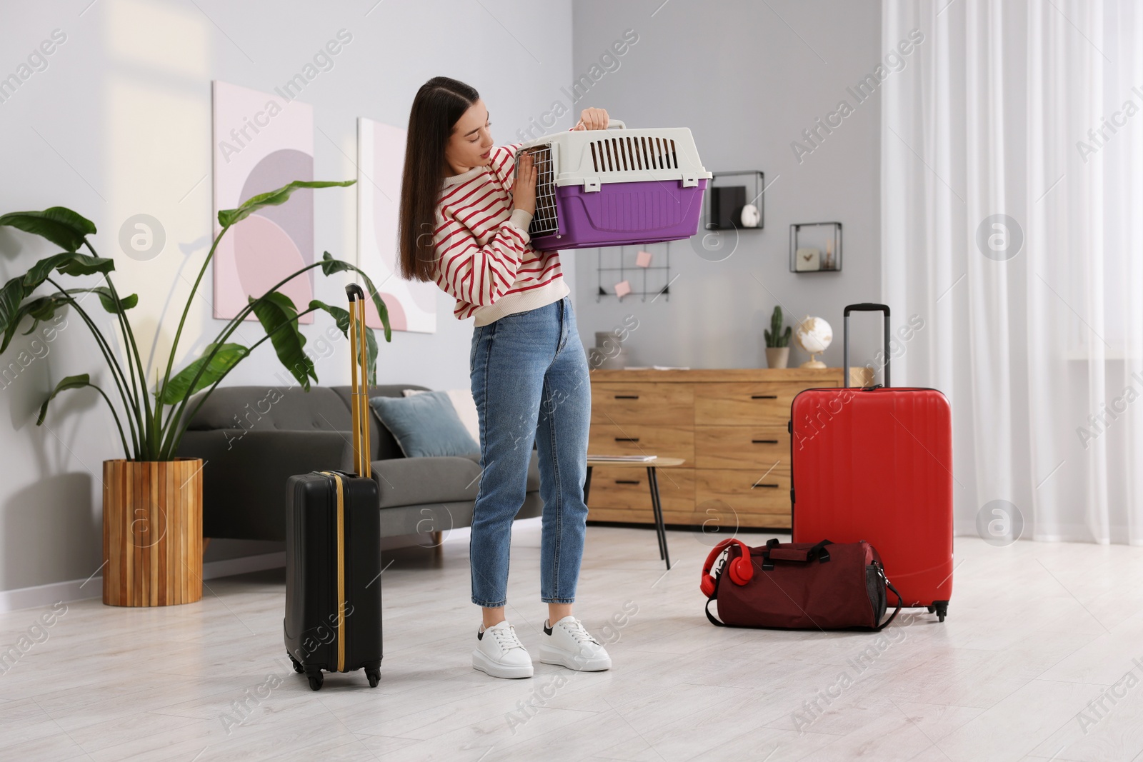 Photo of Travelling with pet. Woman looking at carrier with her dog indoors