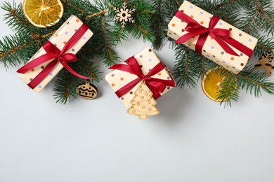 Photo of Flat lay composition with Christmas gift boxes and fir branches on grey background. Space for text