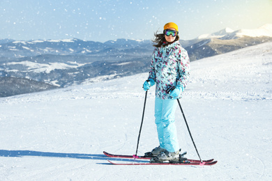 Photo of Female skier on snowy slope in mountains. Winter vacation