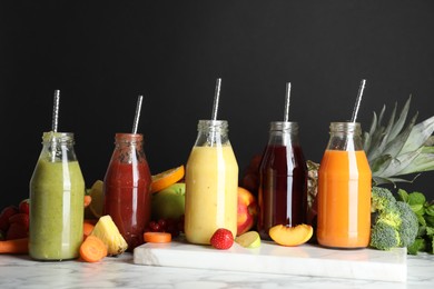 Photo of Bottles of delicious juices and fresh fruits on white marble table