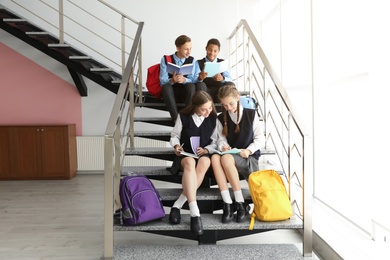 Photo of Teenage students in stylish school uniform on stairs indoors