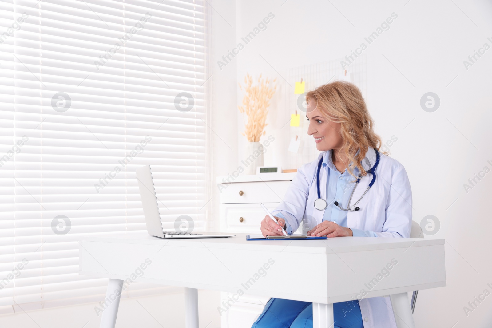 Photo of Doctor with laptop consulting patient in clinic. Online medicine concept