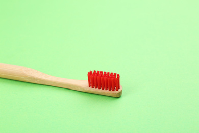 Photo of Natural bamboo toothbrush with soft bristles on green background