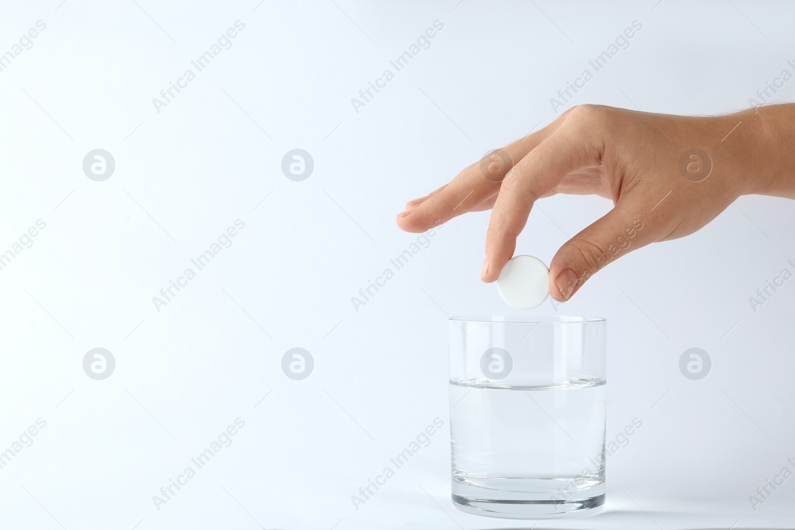 Photo of Woman putting tablet into glass of water on white background, space for text