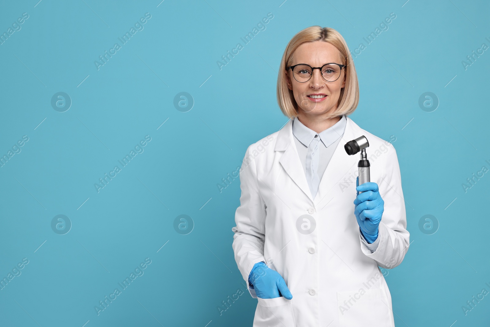 Photo of Dermatologist with dermatoscope on light blue background, space for text