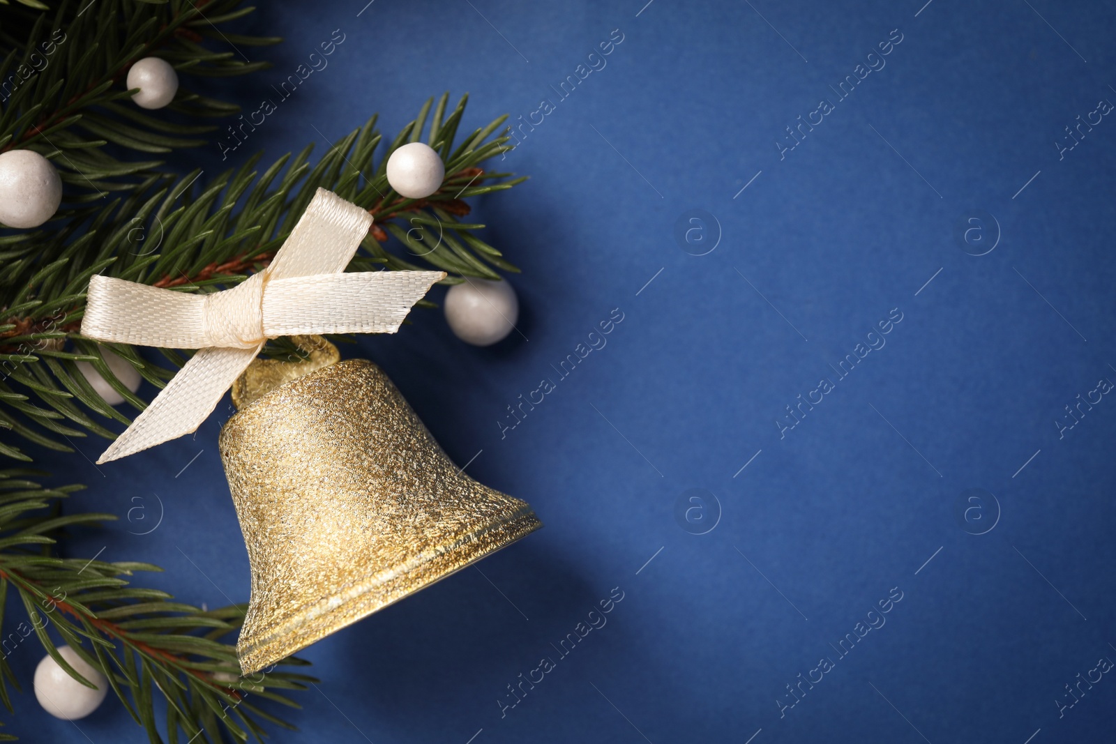 Photo of Bell and fir branches on blue background, flat lay with space for text. Christmas decor