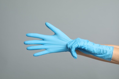 Photo of Doctor wearing medical gloves on grey background, closeup