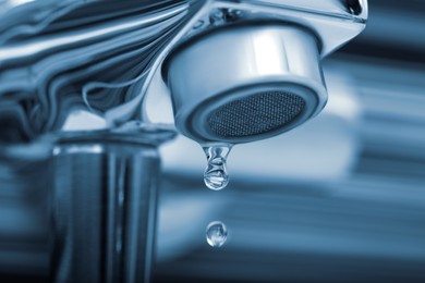 Image of Water drops falling down from tap on blurred background, closeup