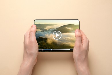Image of Woman using tablet to watch video on beige background, closeup