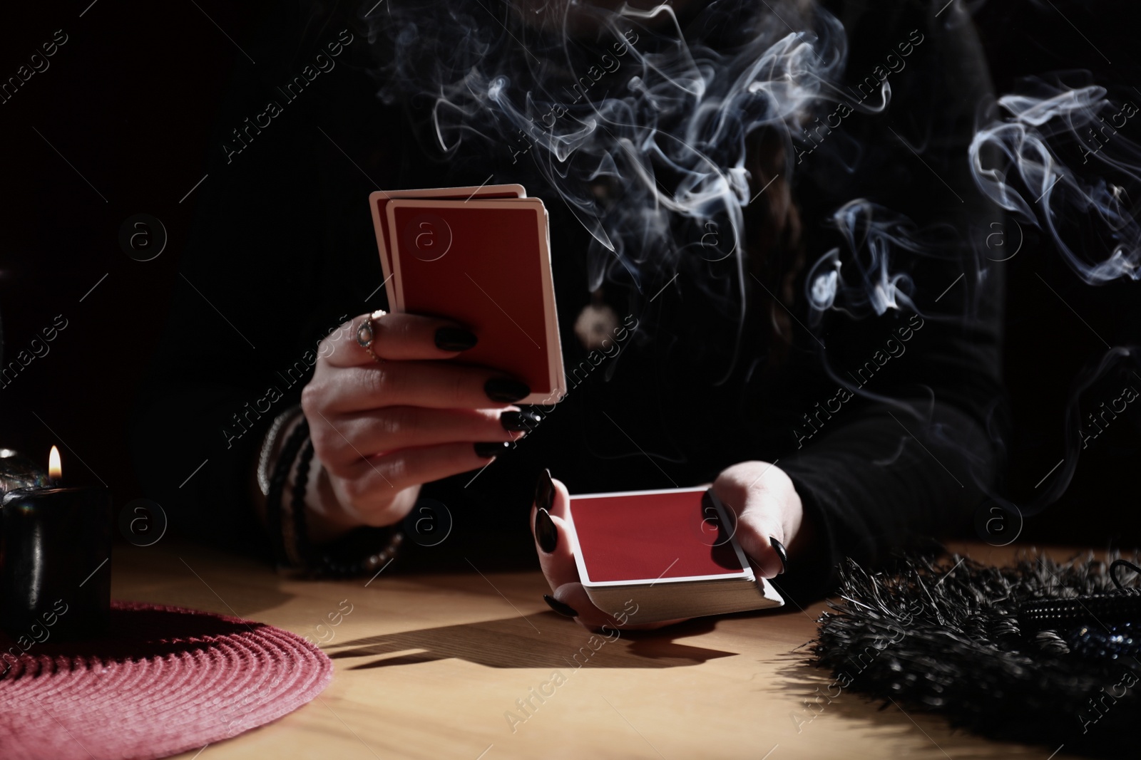 Photo of Soothsayer predicting future with cards at table indoors, closeup