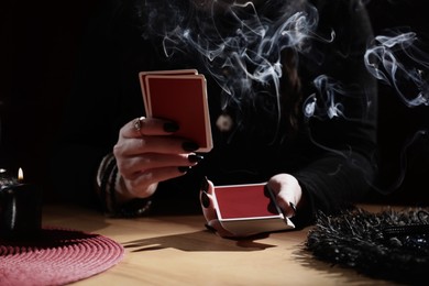 Soothsayer predicting future with cards at table indoors, closeup