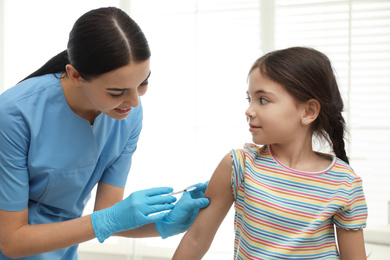 Photo of Doctor vaccinating little child in modern clinic