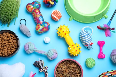 Photo of Flat lay composition with different pet toys and feeding bowls on light blue background