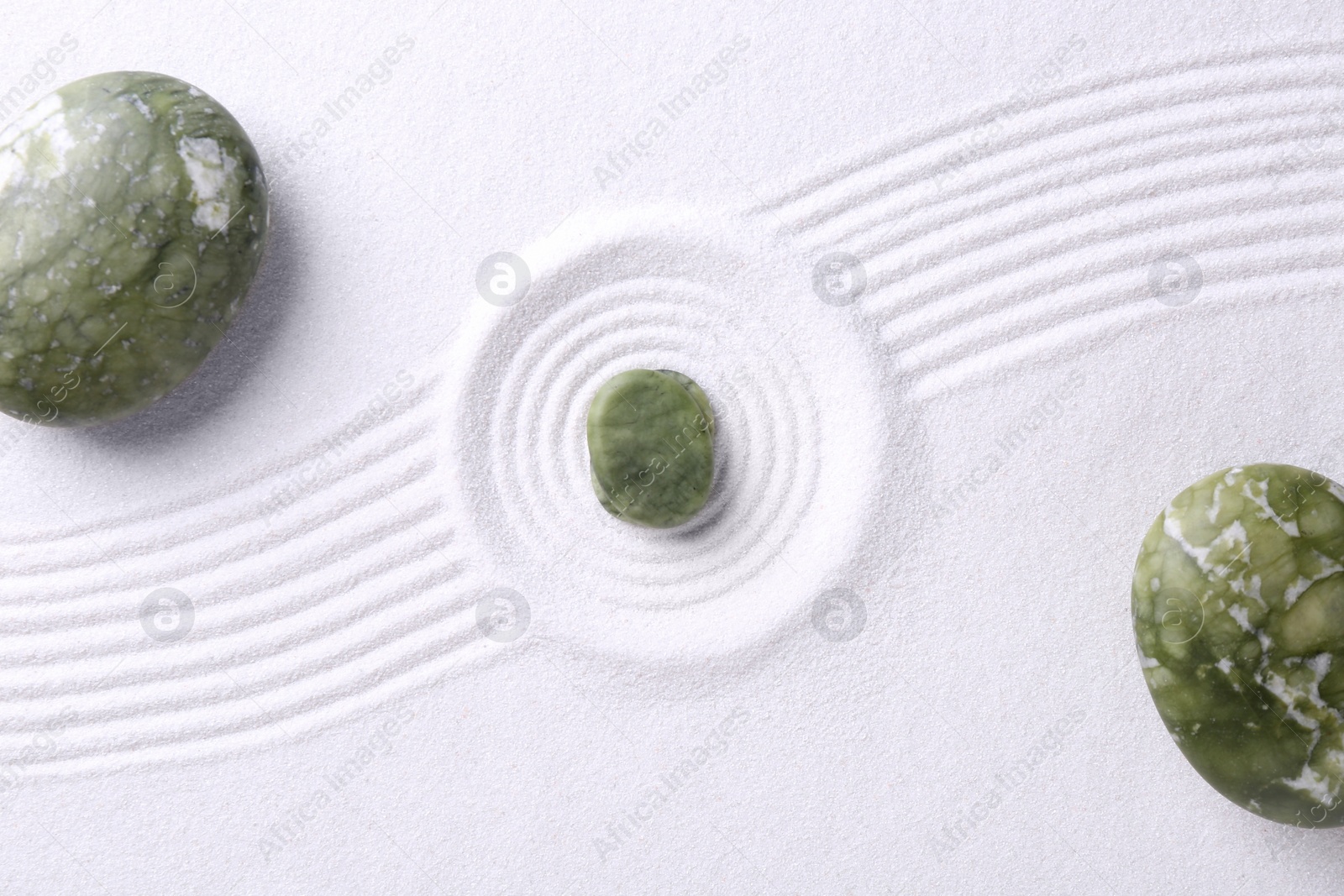 Photo of Zen concept. Stones and pattern on white sand, flat lay