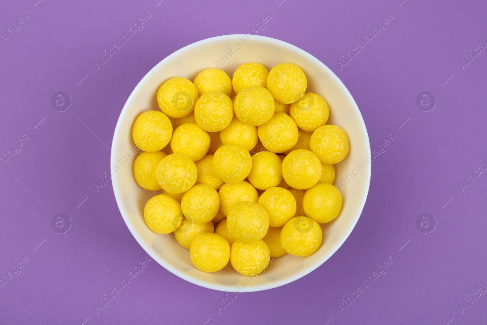 Photo of Delicious lemon drops on purple background, top view