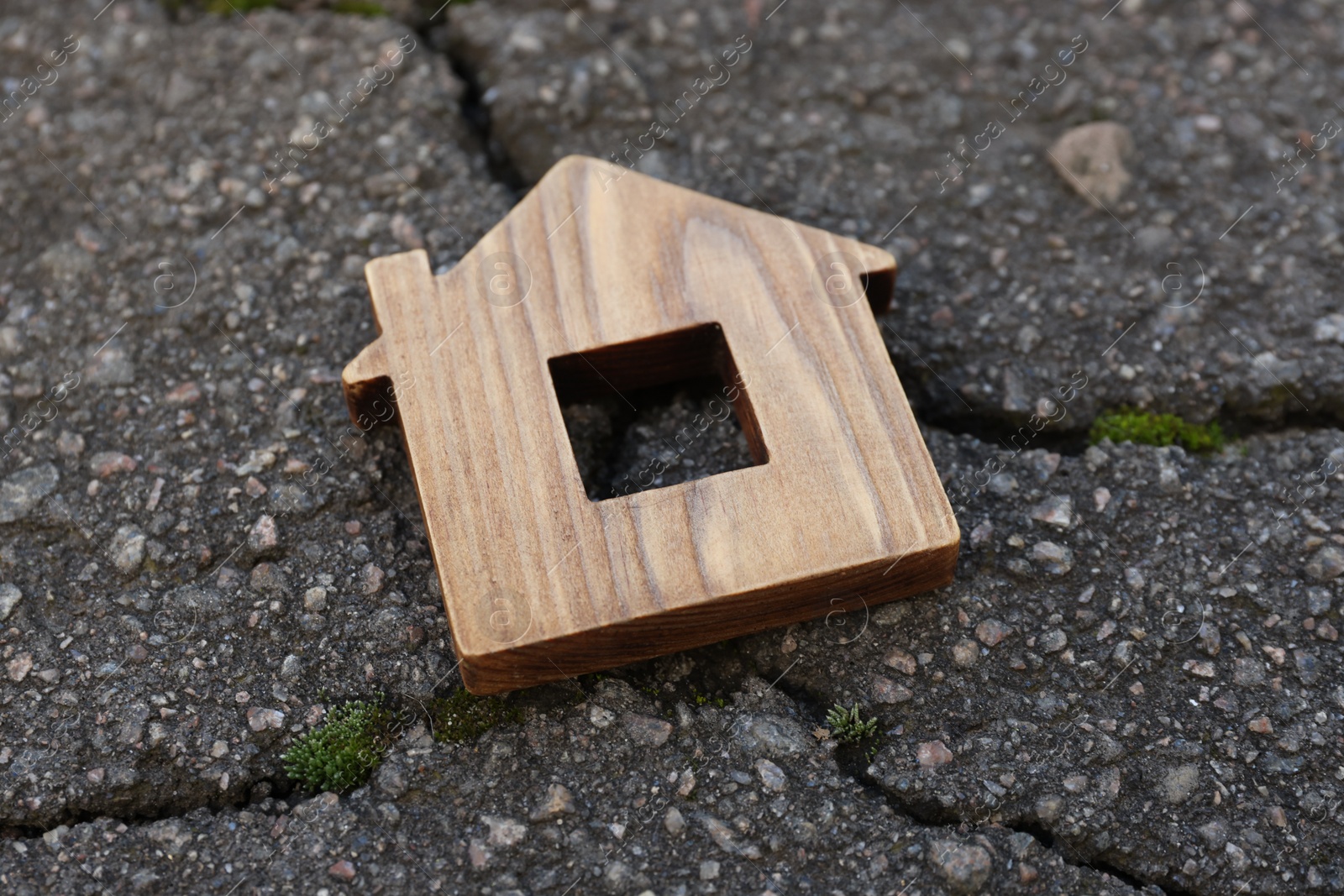 Photo of Wooden house model on cracked asphalt. Earthquake disaster