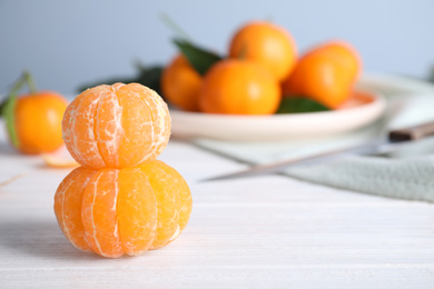 Photo of Peeled ripe tangerines on white wooden table. Space for text