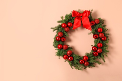 Photo of Beautiful Christmas wreath with festive decor on coral wall, space for text