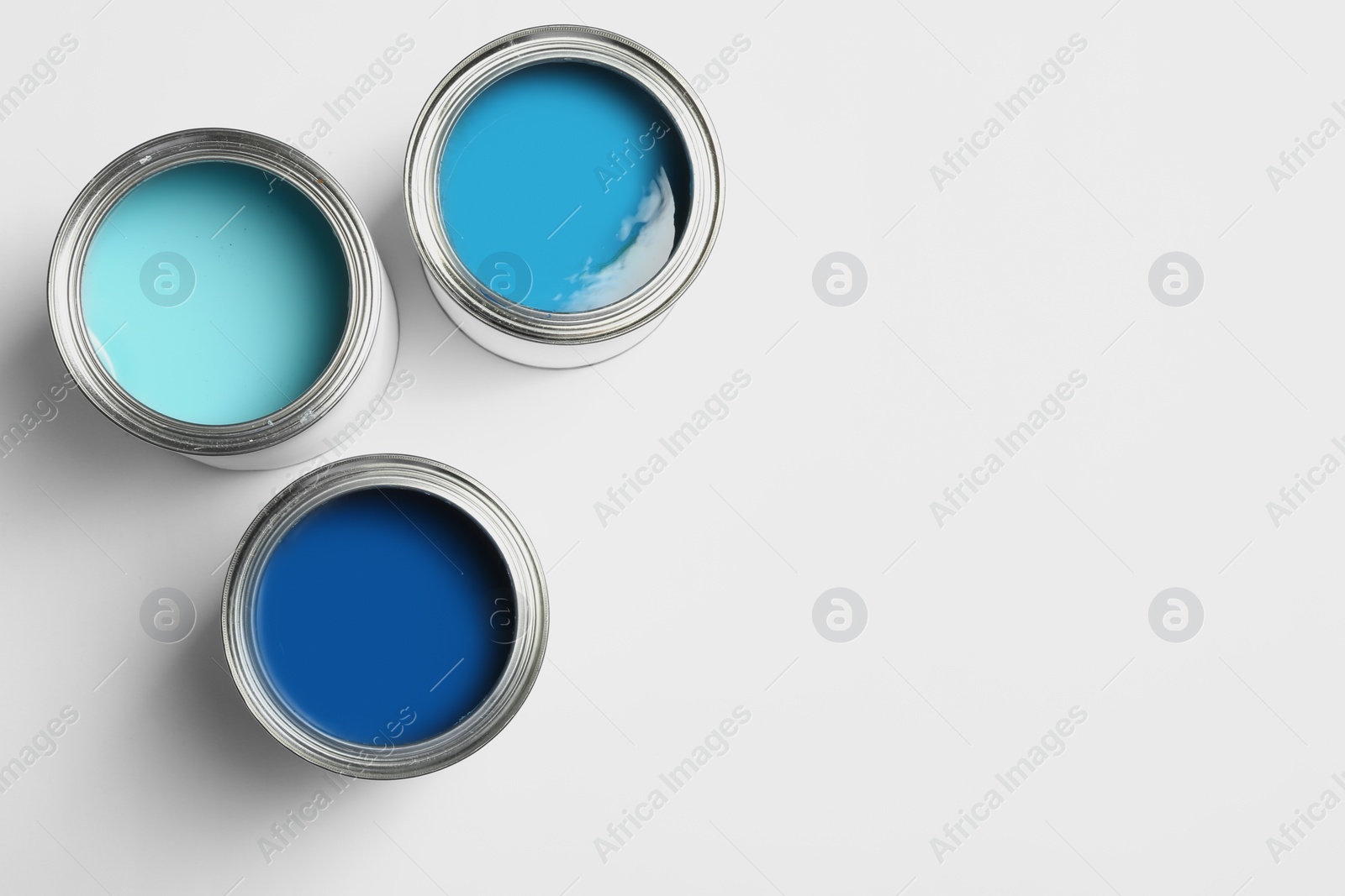 Photo of Open paint cans on white background, top view. Space for text