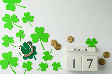 Photo of Flat lay composition with clover leaves and block calendar on white wooden background, space for text. St. Patrick's day