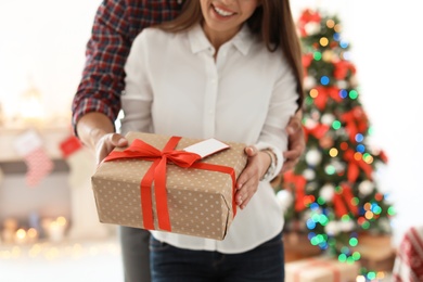 Photo of Young couple with Christmas gift at home