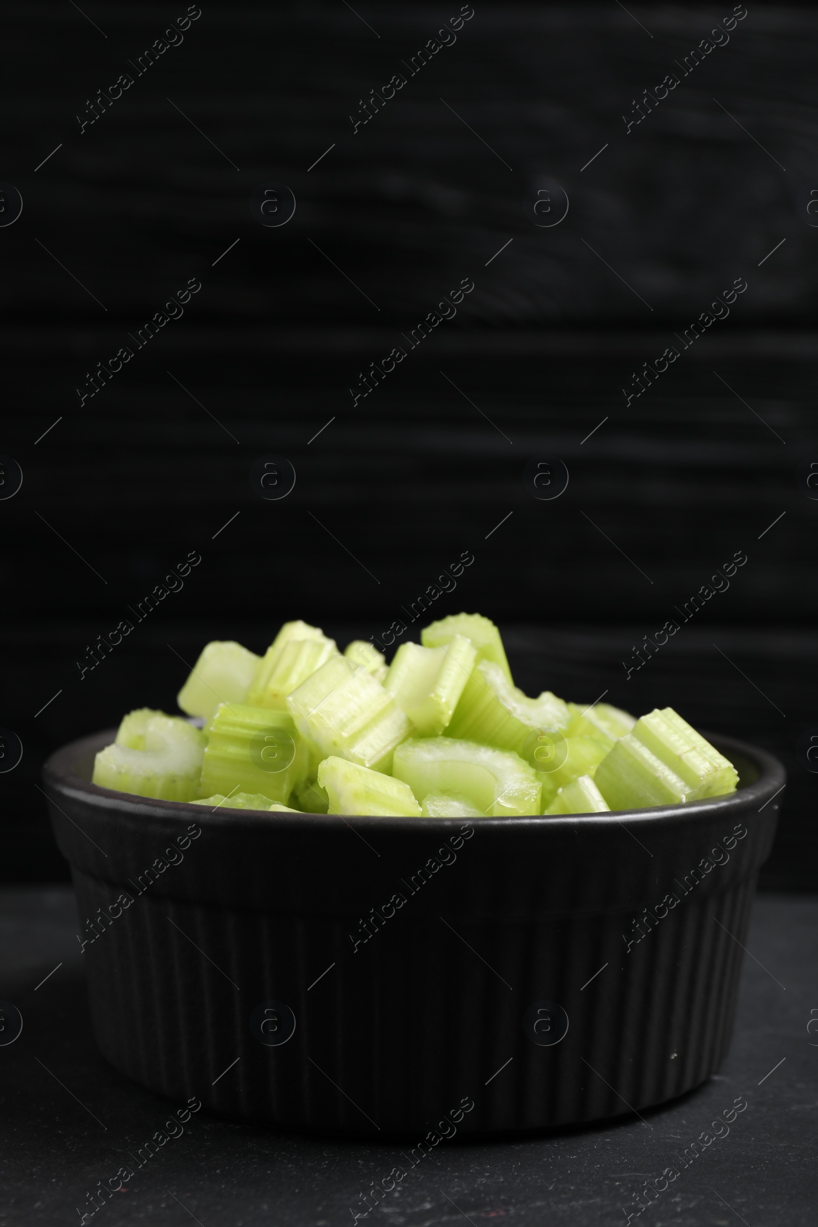 Photo of One bowl of fresh cut celery on grey table, closeup