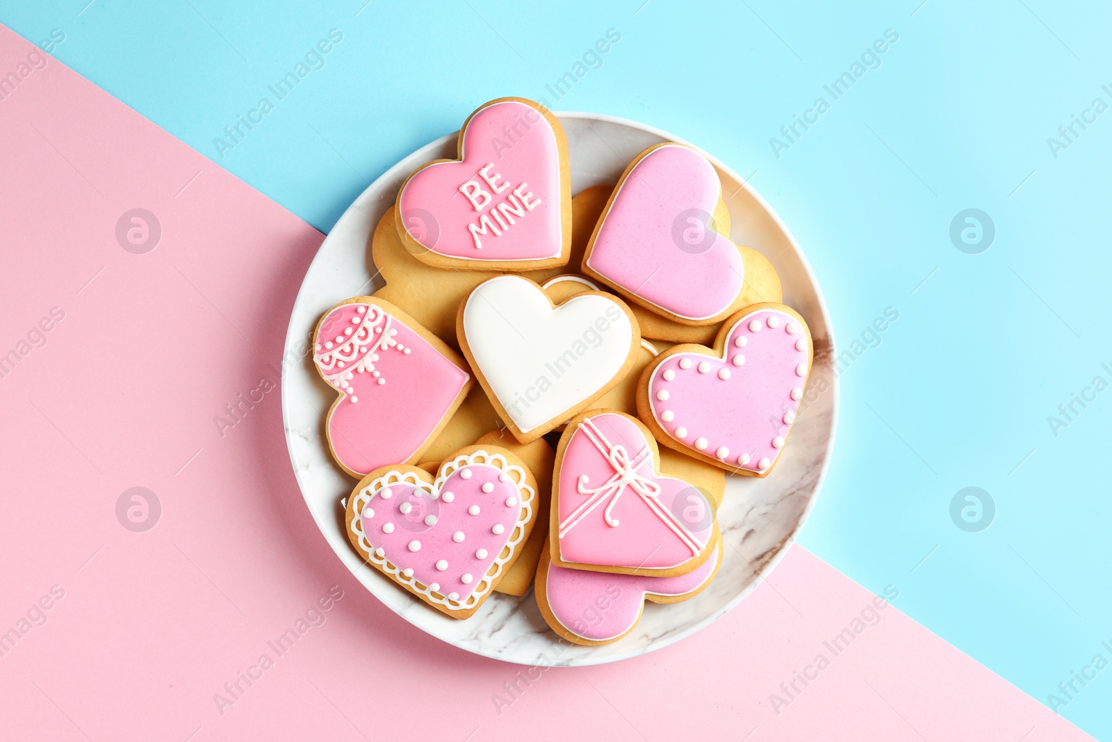 Photo of Plate with decorated heart shaped cookies on color background, top view