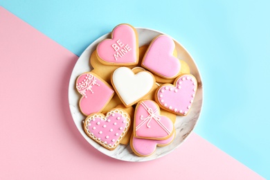 Photo of Plate with decorated heart shaped cookies on color background, top view