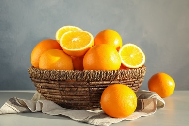 Fresh juicy oranges in wicker basket on table