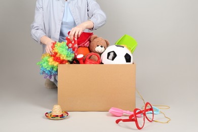 Woman with box of unwanted stuff on grey background, closeup