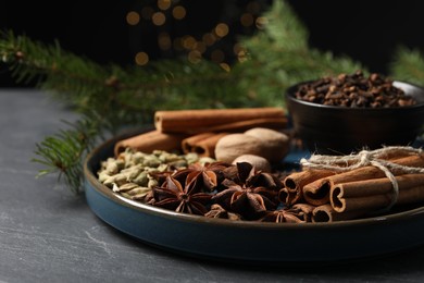 Photo of Dishware with different spices and fir branches on gray table, closeup