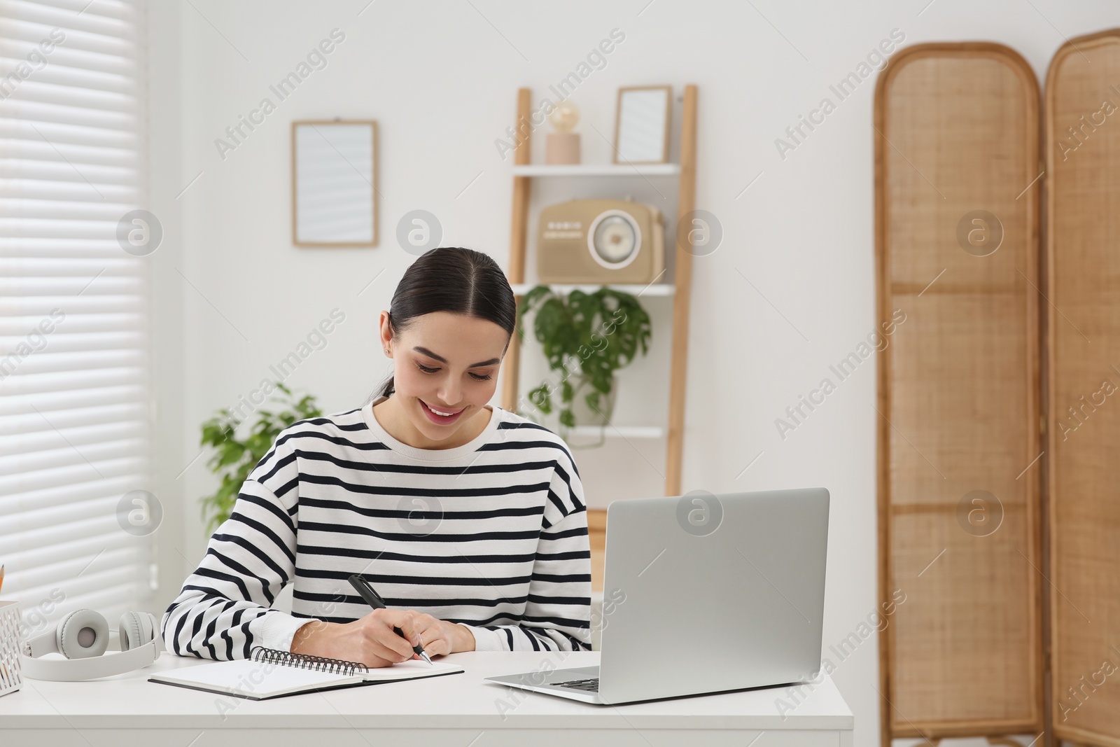 Photo of Online translation course. Student writing near laptop at home