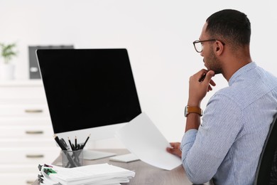 Businessman working with documents at wooden table in office