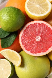 Photo of Different fresh citrus fruits and leaves as background, top view