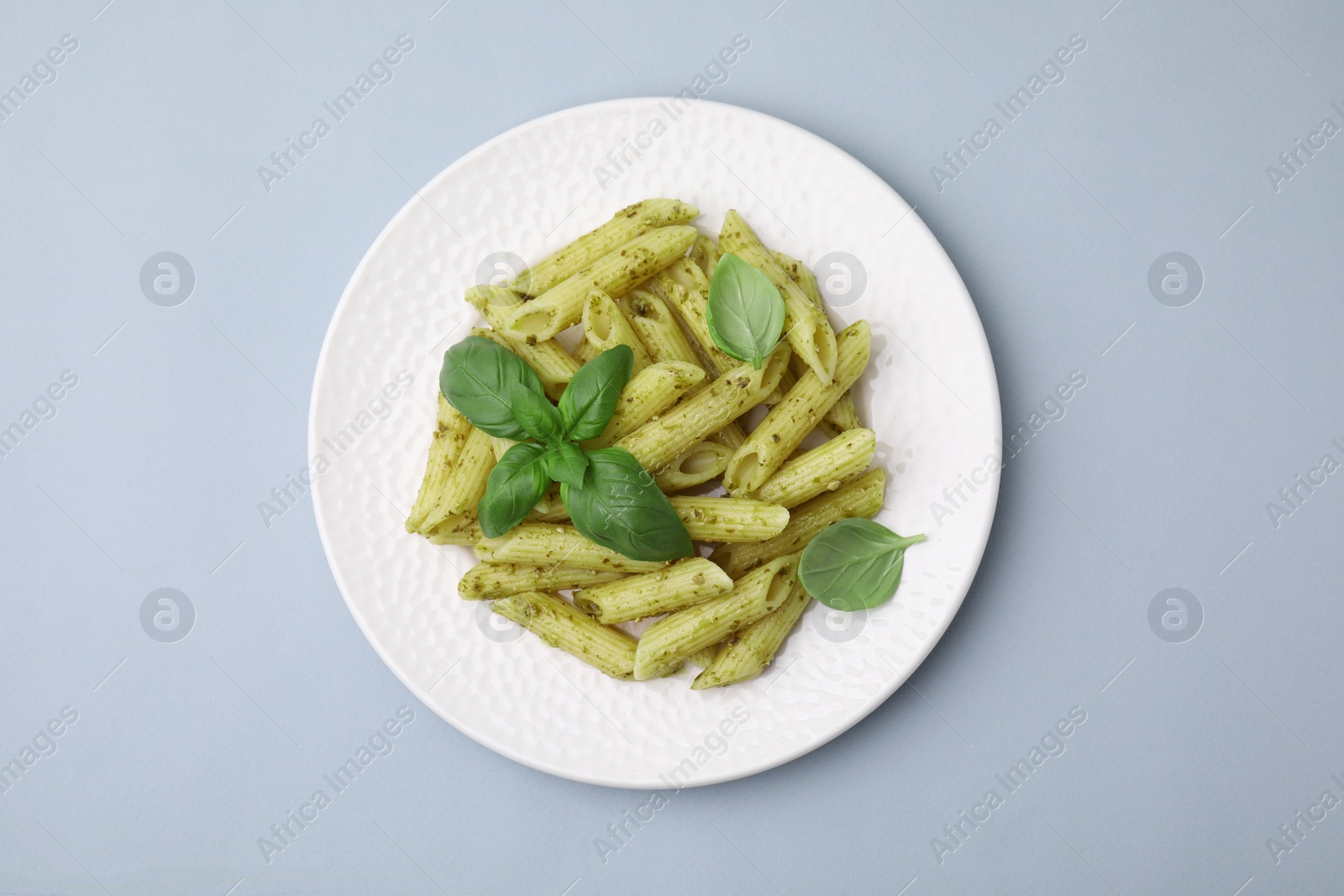 Photo of Delicious pasta with pesto sauce and basil on light grey background, top view