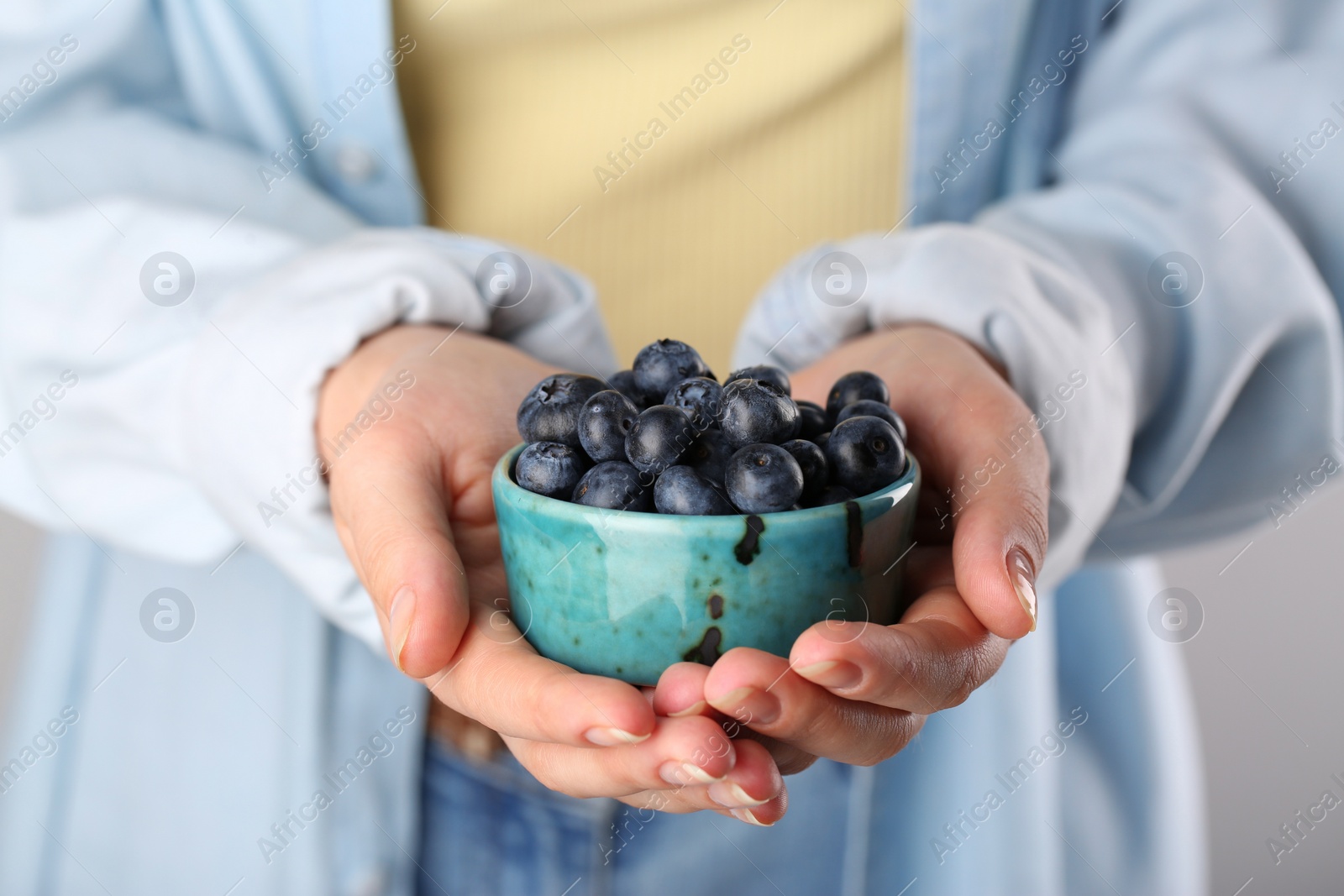 Photo of Woman holding tasty fresh blueberries, closeup view